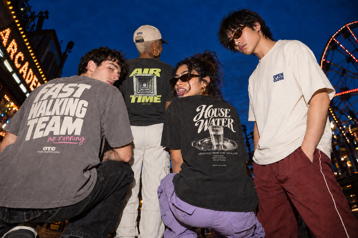 Four friends crouched together under a deep blue evening sky, wearing the Air Time, House Water and other Open To Close tees