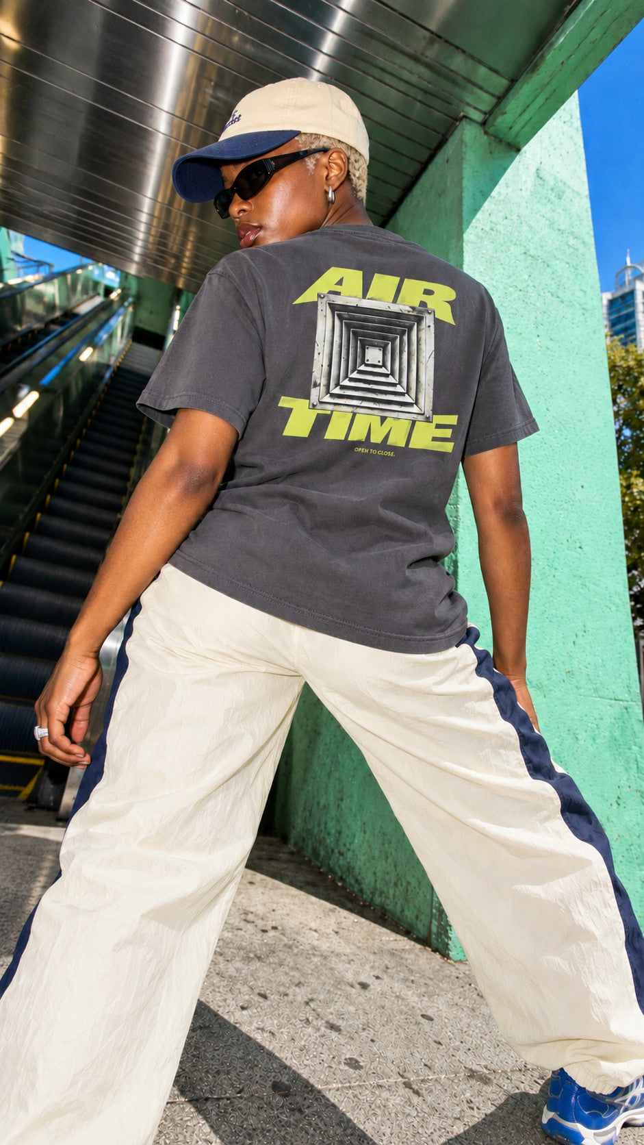 Air Time Tee worn by a model, back view, at the foot of an escalator