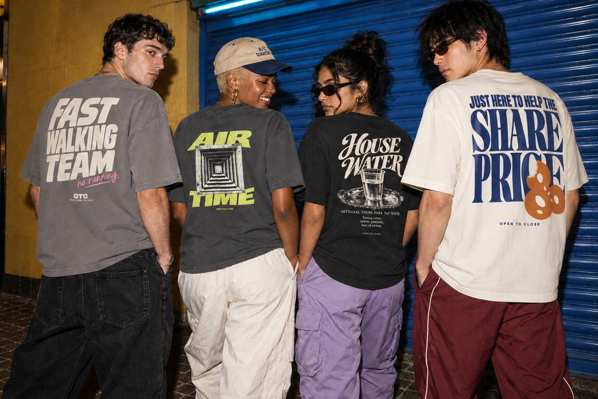 Four friends outside an arcade shutter, backs to camera, in the Fast Walking Team, Air Time, House Water and Share Price tees