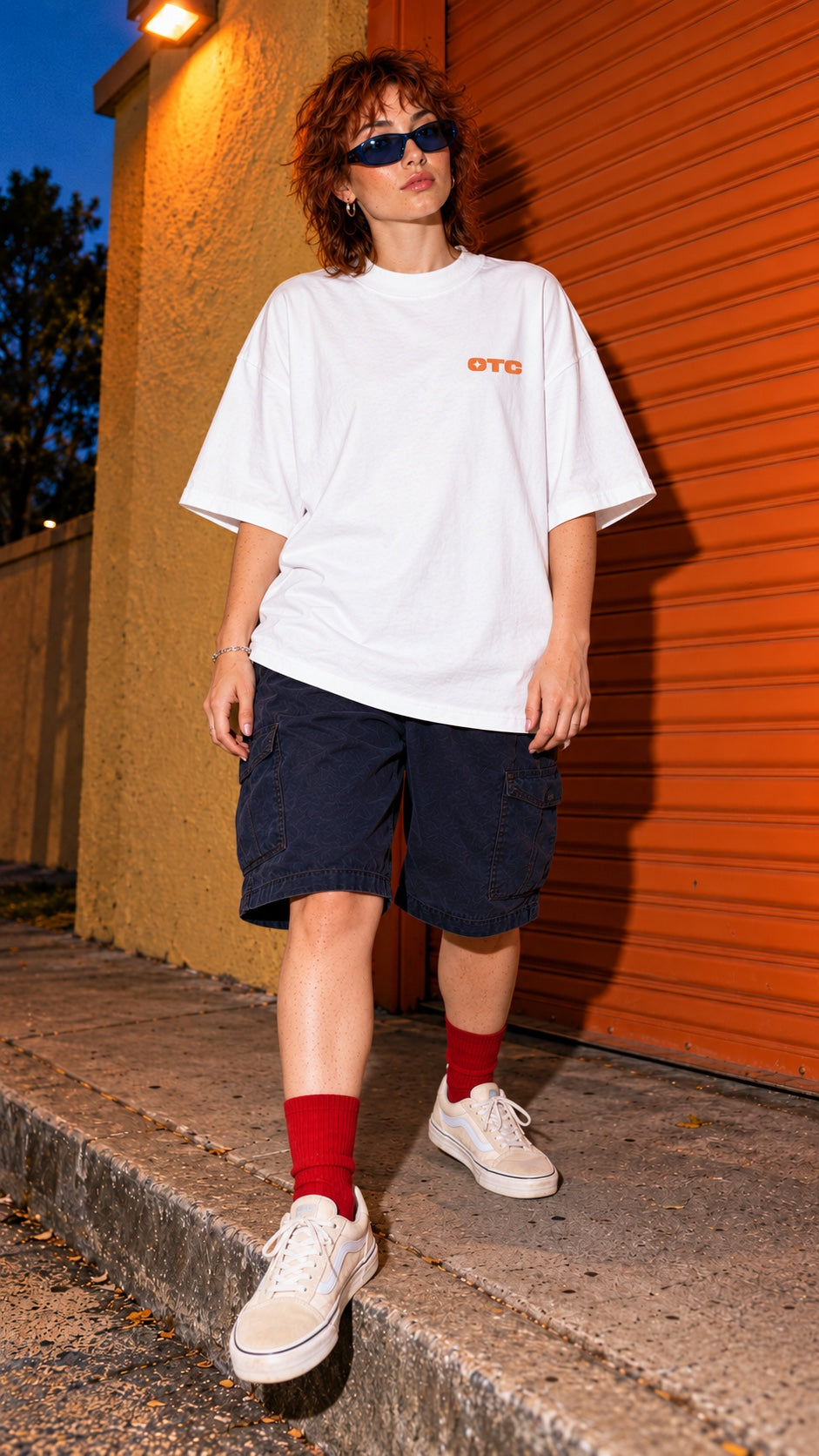 It’s My Pretzel Now Oversized Tee worn by a model, front view, by an orange shutter at dusk