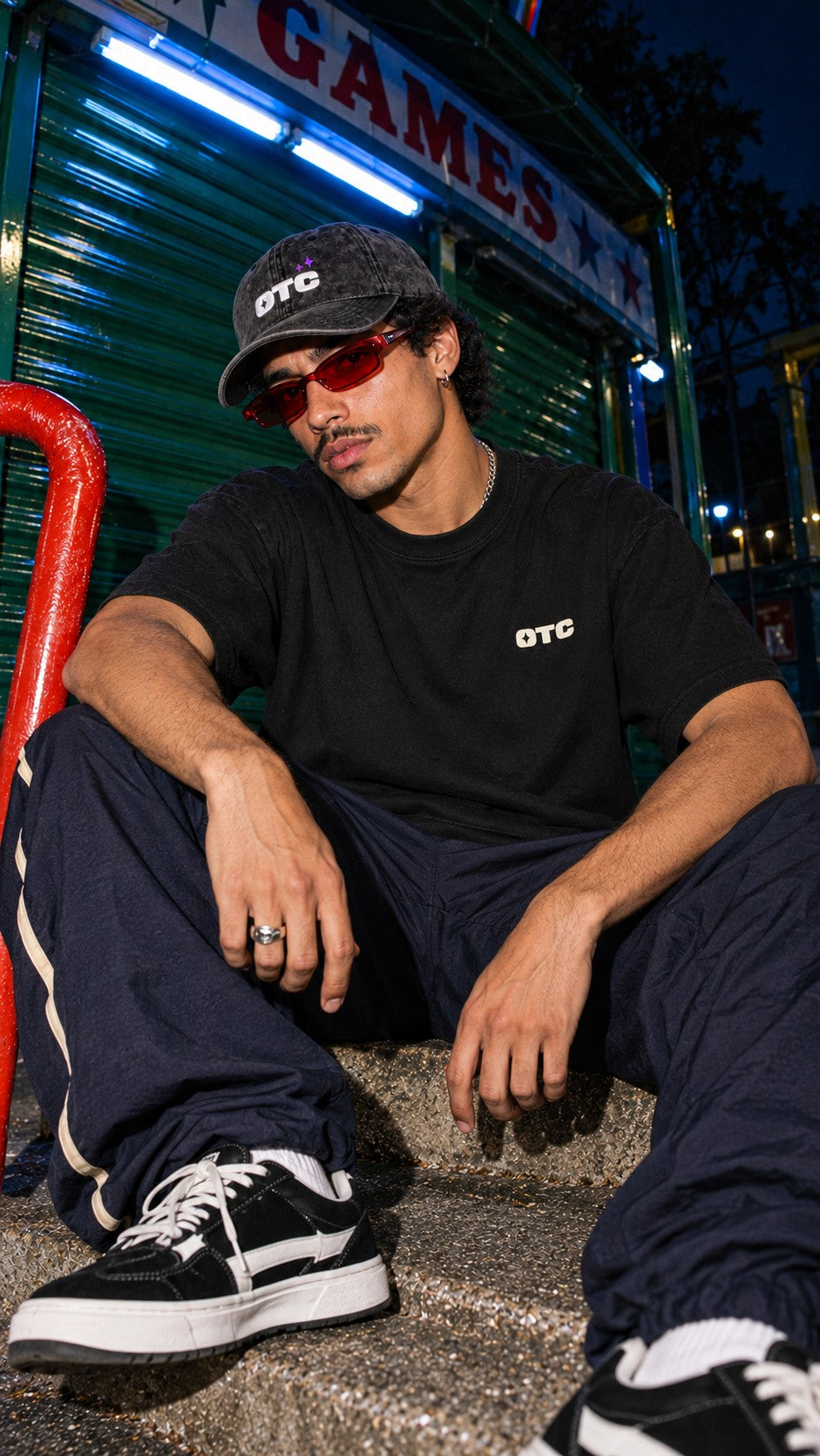 Night Shift Boxy Tee worn by a model, front view, outside the games arcade at night