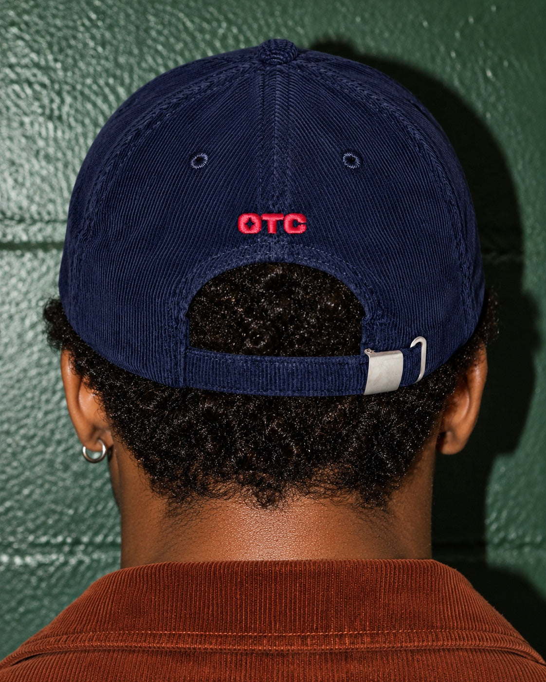 Rope Drop Club Corduroy Cap worn by a model, back view, with a small red OTC above the strap
