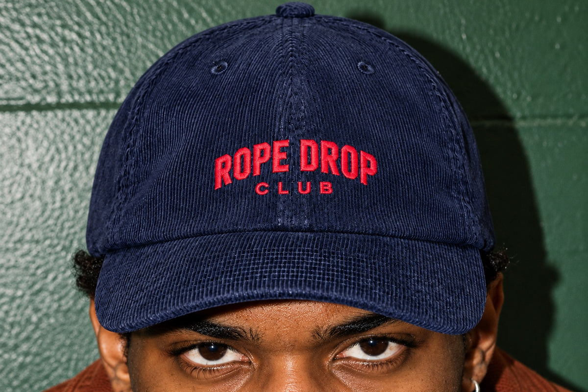 Detail of the red Rope Drop Club embroidery on the navy corduroy cap