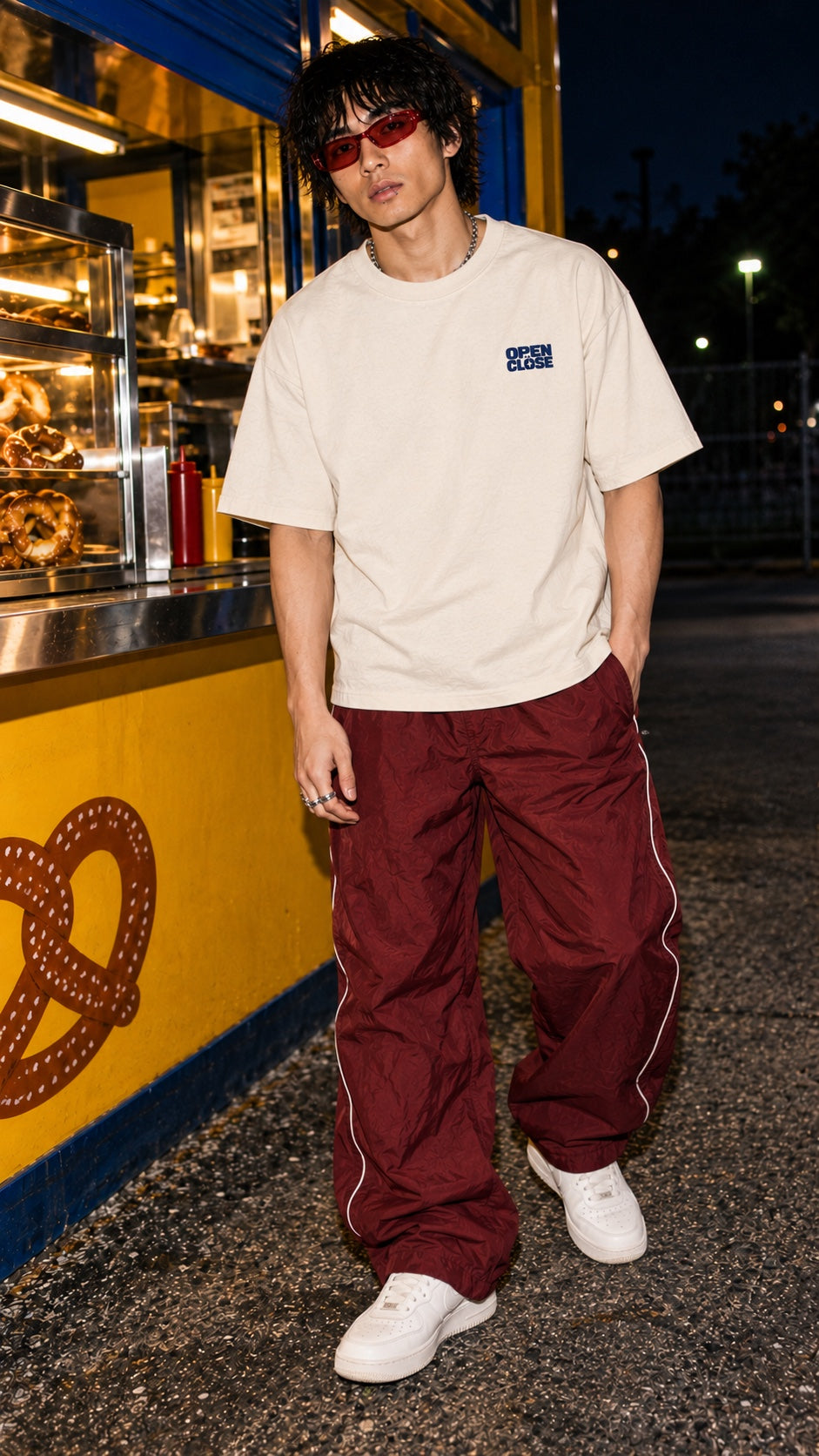 Share Price Boxy Tee worn by a model, front view, at a pretzel stand at night