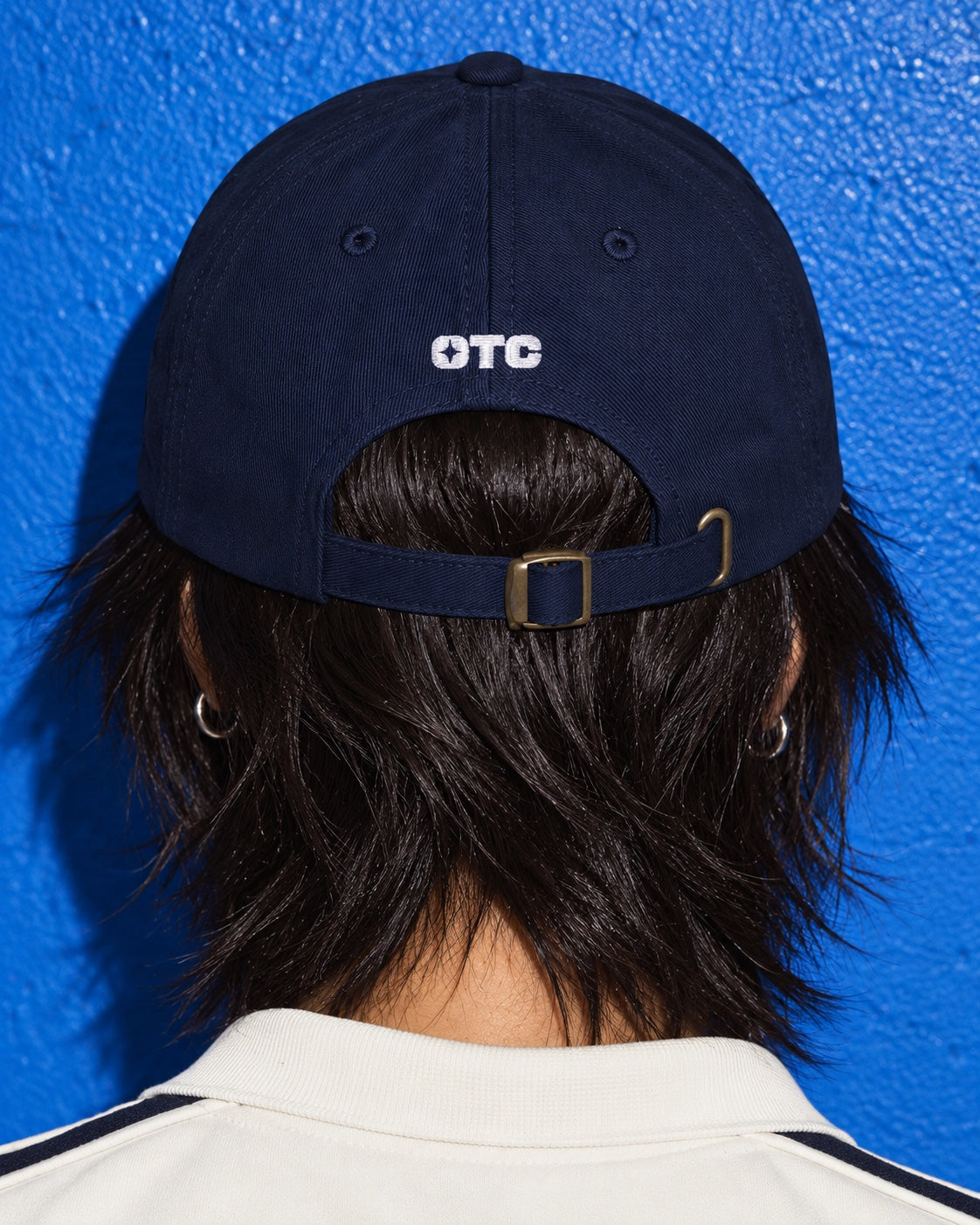 Solo Cap worn by a model, back view, with a small white OTC above the adjustable strap