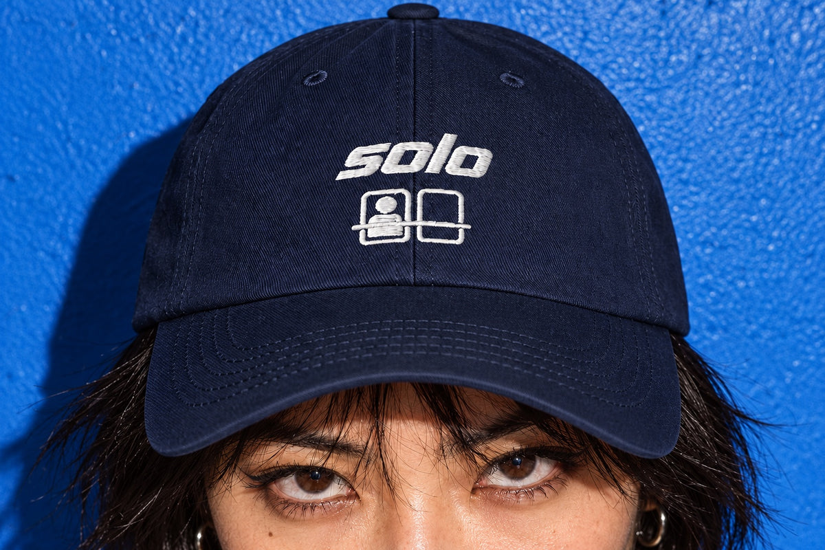 Detail of the Solo Cap’s white “solo” and ride-seat embroidery on navy cotton twill