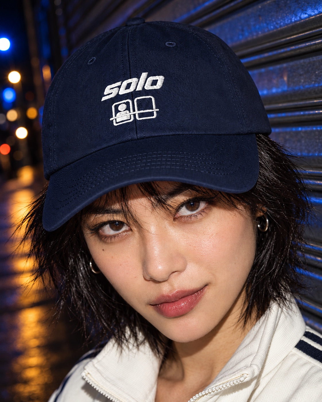 Solo Cap in navy worn by a model on a street at night, front view
